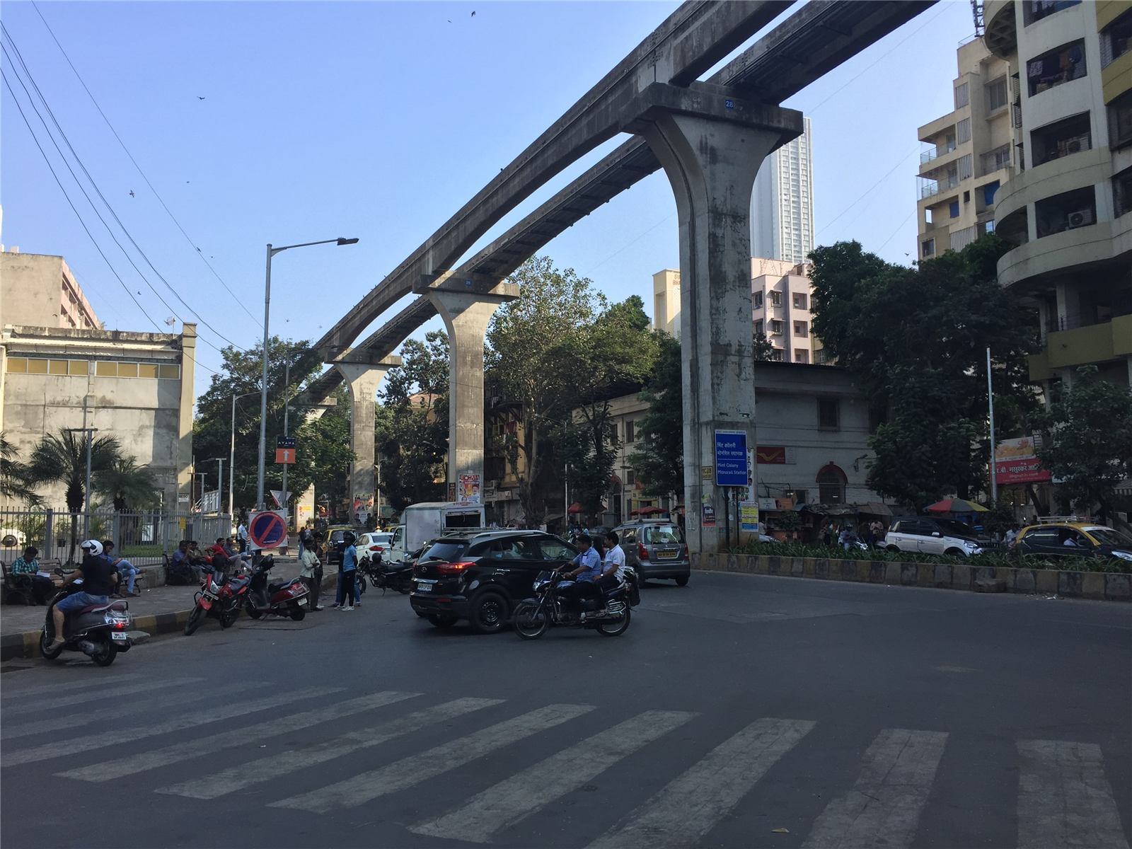 A busy Mumbai street under an elevated metro line
